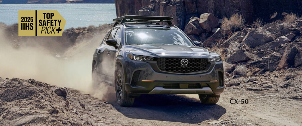Mazda CX-50 2025 gris roulant hors route le long d’un lac, certifié IIHS Top Safety Pick+ pour une sécurité exceptionnelle